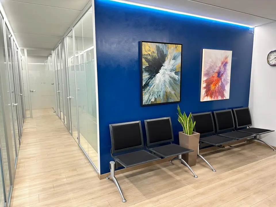 Sala d’attesa dello Studio Legale Avanzi a Verona, con parete blu e sedute nere, e il corridoio con le stanze separate da pareti in vetro